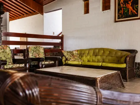 Sala de convivência interna com sofás e poltronas de vime, ambiente acolhedor e seguro para os pacientes